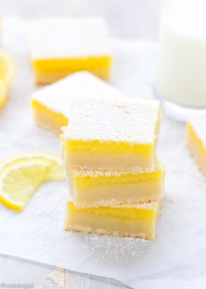 Thick and tangy classic lemon bars, perfectly cut on top of each other, dusted with powder sugar