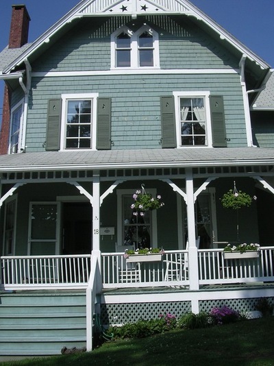 Экстерьер дома с зеленым фасадом и белыми элементами