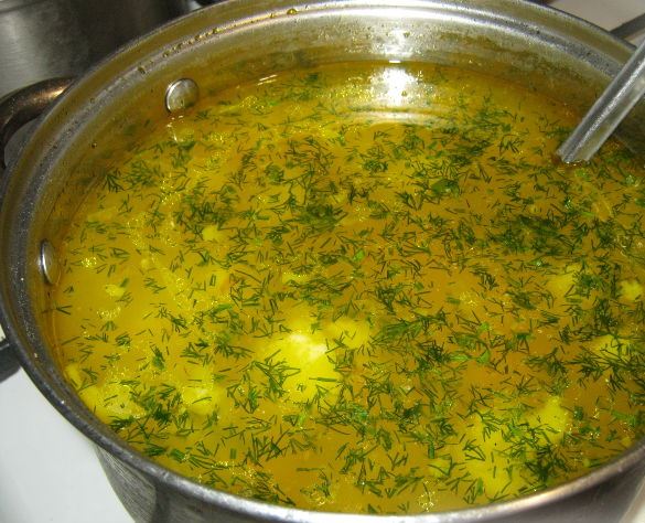 Суп с фрикадельками и свежим укропом в большой металлической кастрюле